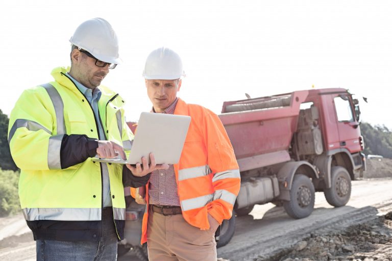 Two men in a construction site using a laptop